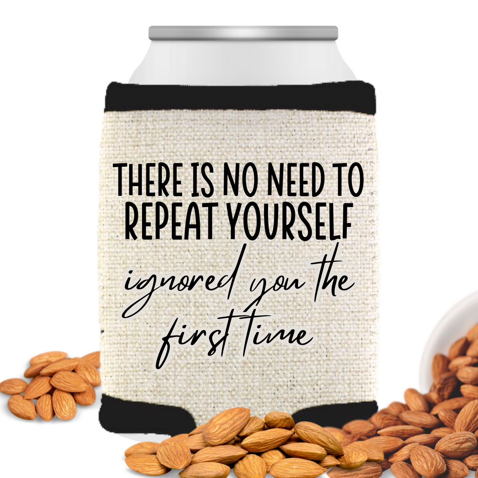 A beige can cooler with black trim and text that reads 'There is no need to repeat yourself; I ignored you the first time' on a white background, with a can behind it and almonds scattered around.