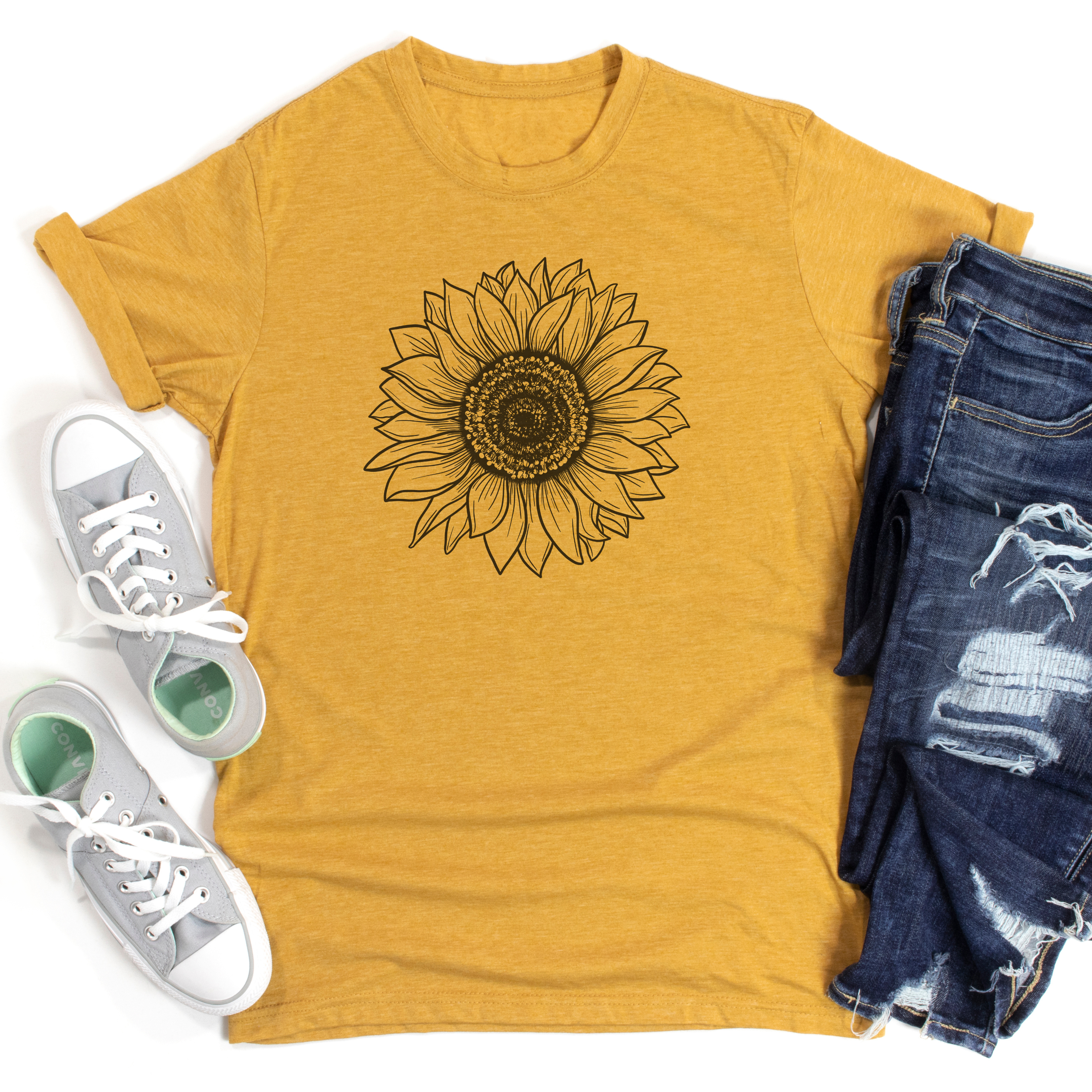 Yellow t-shirt with sunflower design, white sneakers, and blue jeans on a white background