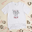White t-shirt with dancing skeletons design and 'Jolly AF' text on a festive background with candy canes and cookie cutters.
