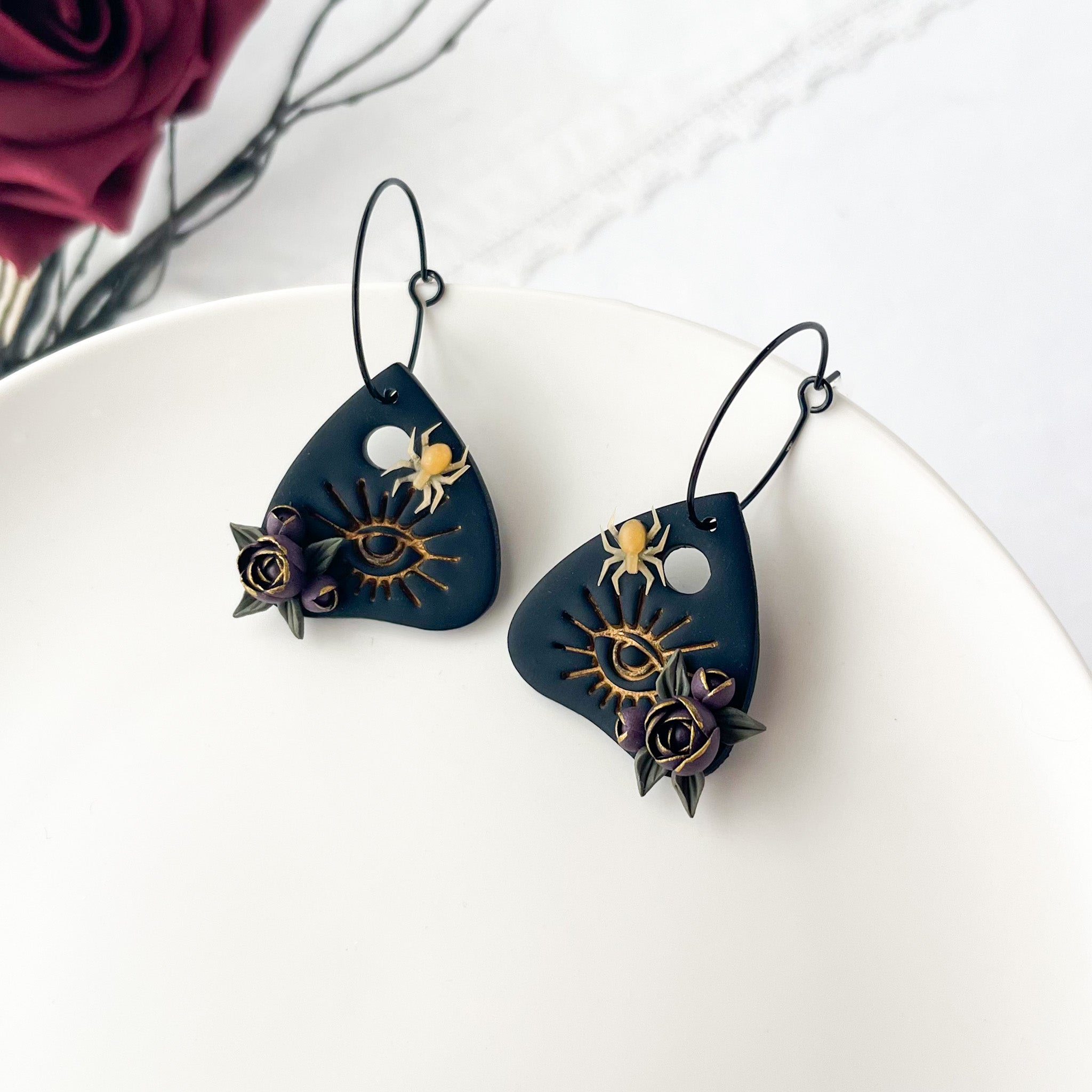 Pair of black earrings with intricate designs on a white surface.