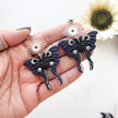 Moth-shaped earrings held in a hand with a white background