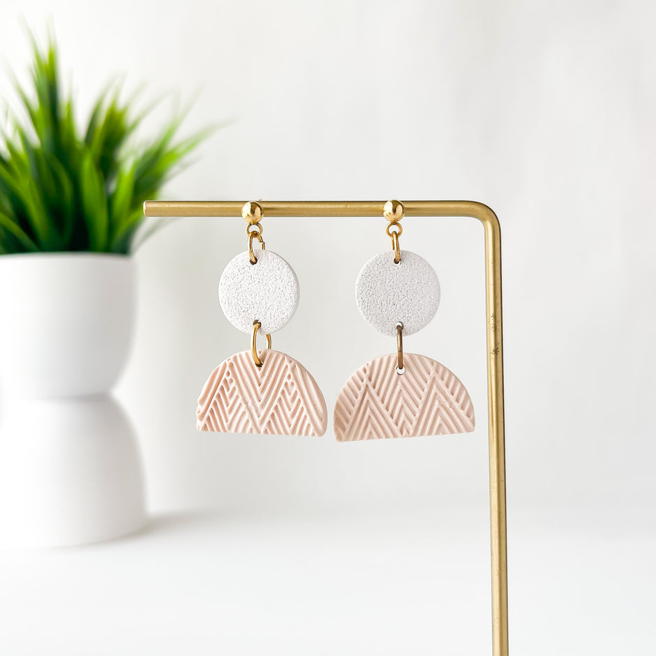 Pair of earrings with geometric design on a gold stand against a white background