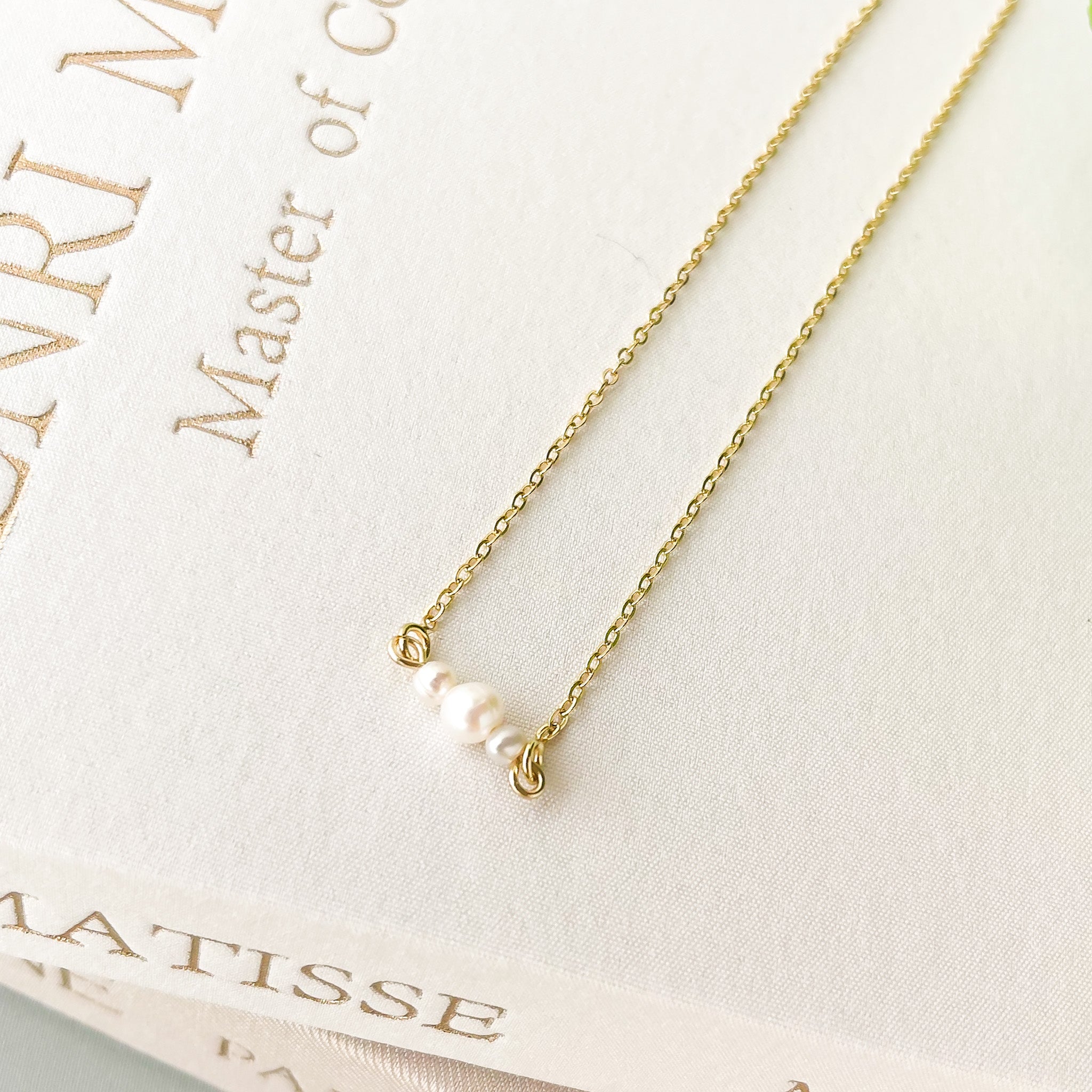 Gold necklace with a pearl pendant on a Matisse jewelry box
