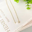 Gold necklace with a pearl pendant on a book with greenery in the background