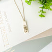 Necklace with a mushroom design pendant on a white surface with text and greenery