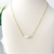 Gold necklace with 3 small pearls on a mannequin bust.