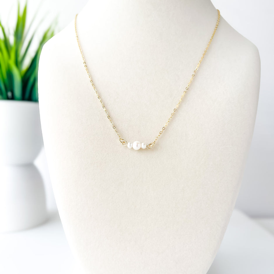 Gold necklace with a pearl on a mannequin against a white background