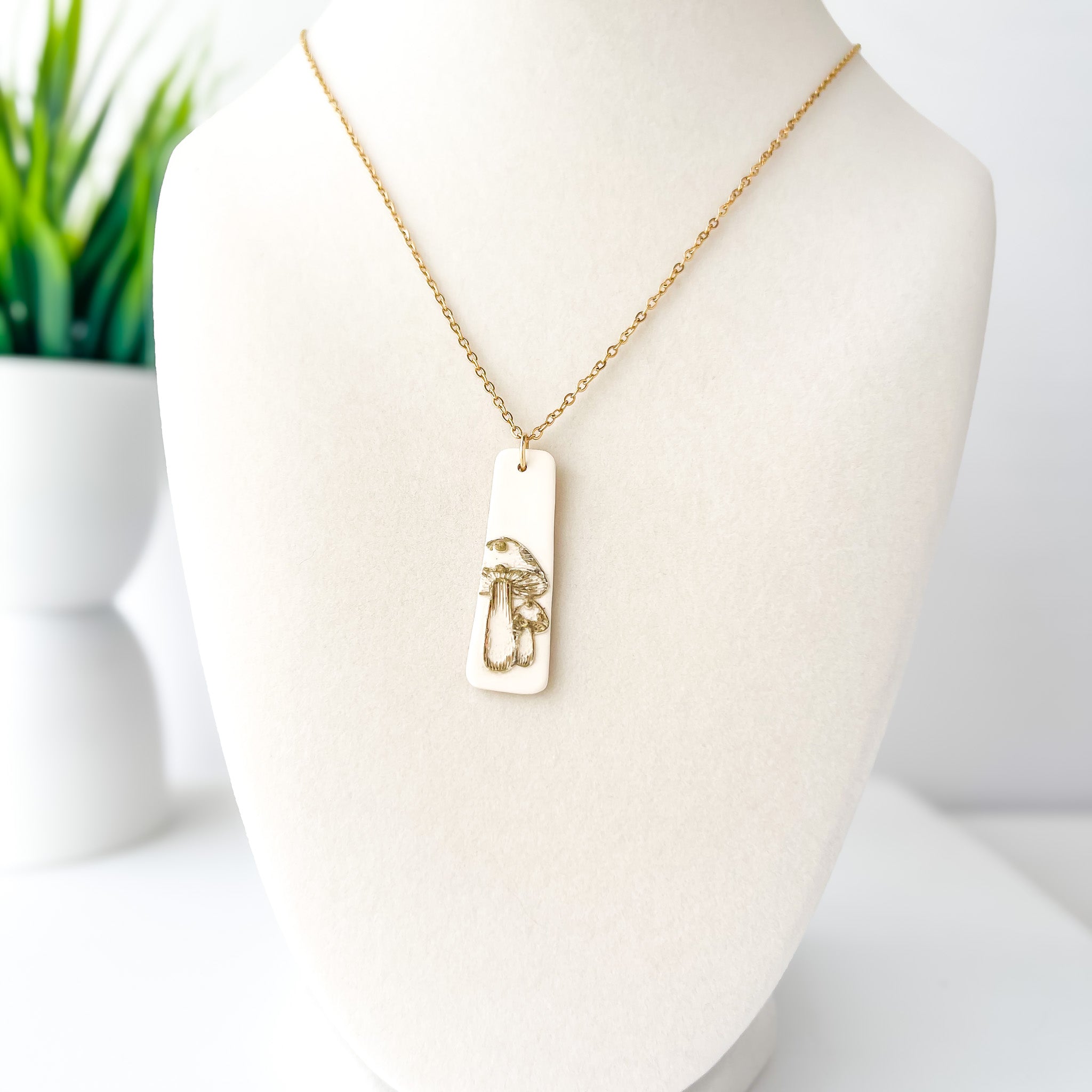 Gold necklace with a pendant on a mannequin bust against a white background