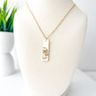 Gold necklace with a pendant on a mannequin bust against a white background