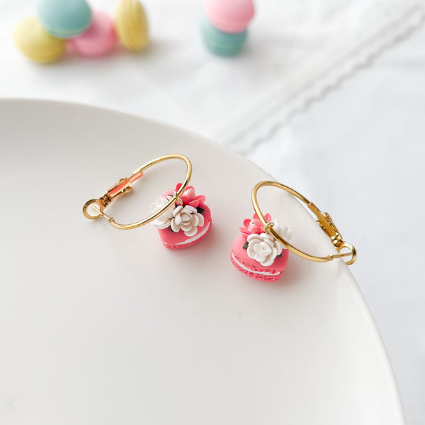 Pink heart macaron earrings with floral details on a white plate