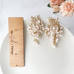 Floral earrings on a white plate with a wooden ruler for scale, against a light background.