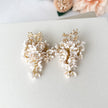 Pair of floral earrings with gold accents on a light gray surface.
