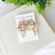 Floral earrings on a card with 'My Sister's Things' branding, placed on a light surface with greenery.