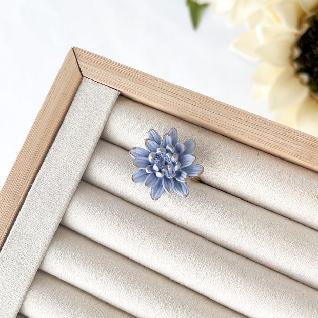 Blue flower-shaped earring on a wooden jewelry display box with beige interior.