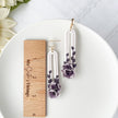 Floral earrings on a white plate with a wooden ruler for scale.