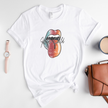 White t-shirt with colorful lip graphic and 'Wild Child' text, placed on a light surface with accessories.