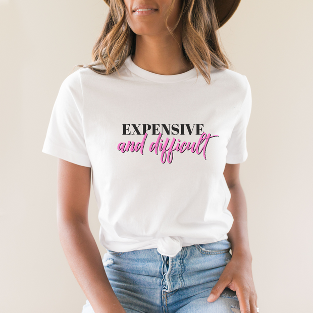 Person wearing a white t-shirt with text 'EXPENSIVE and difficult' in black and pink on a plain background