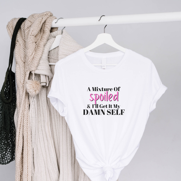 White t-shirt with text on a hanger with a blanket and bag in the background