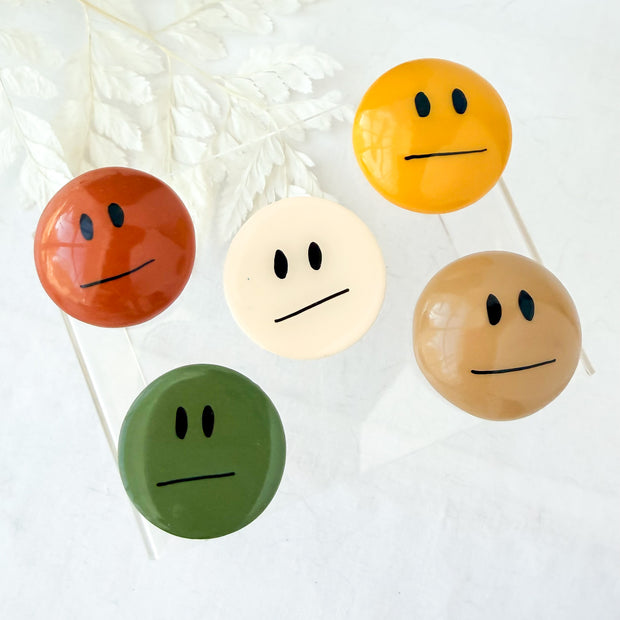 Round polymer clay fridge magnets with neutral faces in mustard, terracotta, cream, tan, and olive green.